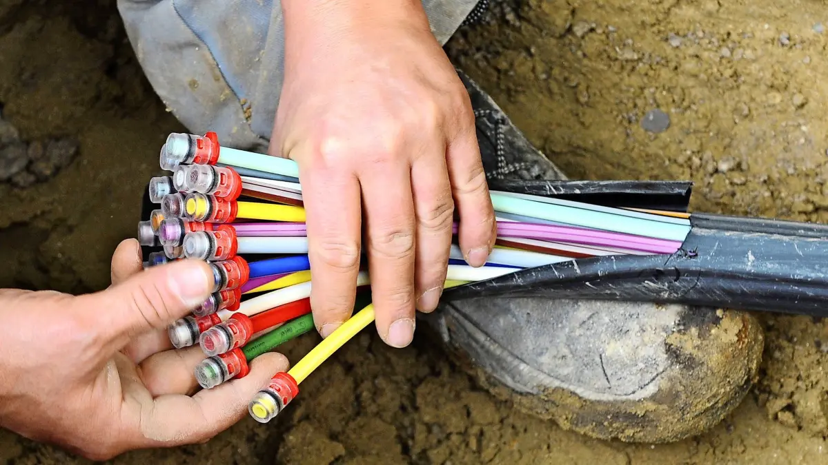 ARCHIV - ILLUSTRATION - Ein Mann fächert 10.05.2010 unter einer Straße in München (Bayern) ein Glasfaser-Kabel mit farbigen Einzelsträngen auseinander. Der Breitbandausbau ist in Brandenburg etwas vorangekommen - aber noch viel zu wenig. «Die Landesregierung hat die Entwicklung einfach verschlafen», sagte der wirtschaftspolitische Sprecher der CDU-Fraktion im Landtag von Brandenburg der Deutschen Presse-Agentur. (zu dpa «CDU-Abgeordneter: Brandenburg hat Breitbandausbau verschlafen» vom 31.12.2017) Foto: Peter Kneffel/dpa +++(c) dpa - Bildfunk+++