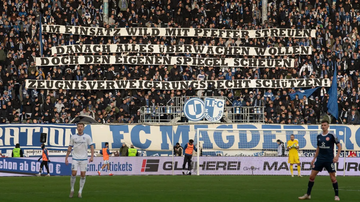 Fußball: 2. Bundesliga, 1. FC Magdeburg — Fortuna Düsseldorf, 17. Spieltag, MDCC–Arena. Magdeburger Fans zeigen einen Spruchbanner „Im Einsatz wild mit Pfeffer streuen — danach alles überwachen wollen — doch den eigenen Spiegel scheuen — Zeugnisverweigerungsrecht schützen!“