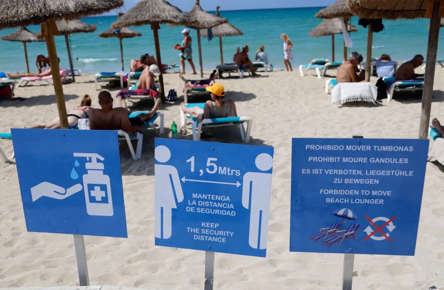 Menschen sonnen sich und schwimmen am Strand von Arenal auf Mallorca. Im Vordergrund ist ein Schild mit dem Hinweis auf die Abstandsregelungen zu sehen. Angesichts erhöhter Ansteckungsgefahren hat die Bundesregierung fast ganz Spanien einschließlich Mallorca als Risikogebiet eingestuft.