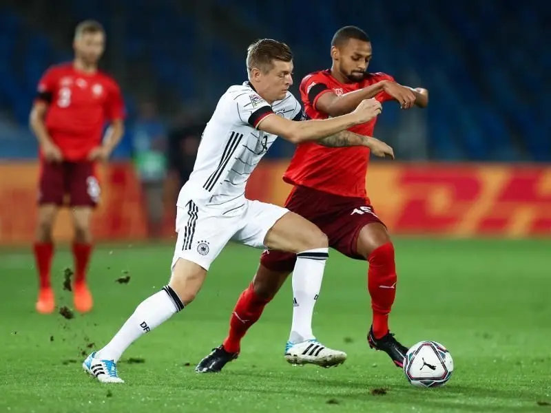 Toni Kroos (l) im Zweikampf mit dem Schweizer Djibril Sow. Foto: Christian Charisius/dpa