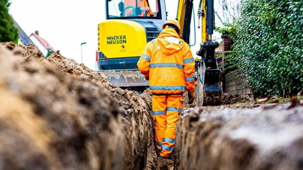 Ein Baggerfahrer erwischte in Michelfeld mit der Schaufel ein Stromkabel.
Arbeiter sind mit Bagger und Spaten an einer Straße mit der Erdverlegung von Glasfaserkabeln beschäftigt. +++ dpa-Bildfunk +++