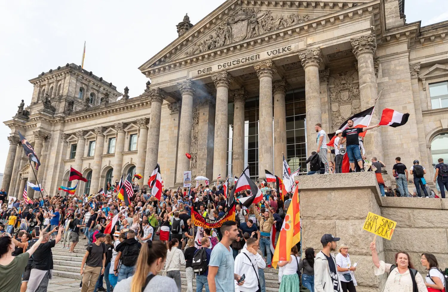 Teilnehmer einer Kundgebung gegen die Corona-Maßnahmen stehen auf den Stufen zum Reichstagsgebäude, zahlreiche Reichsflaggen sind zu sehen.