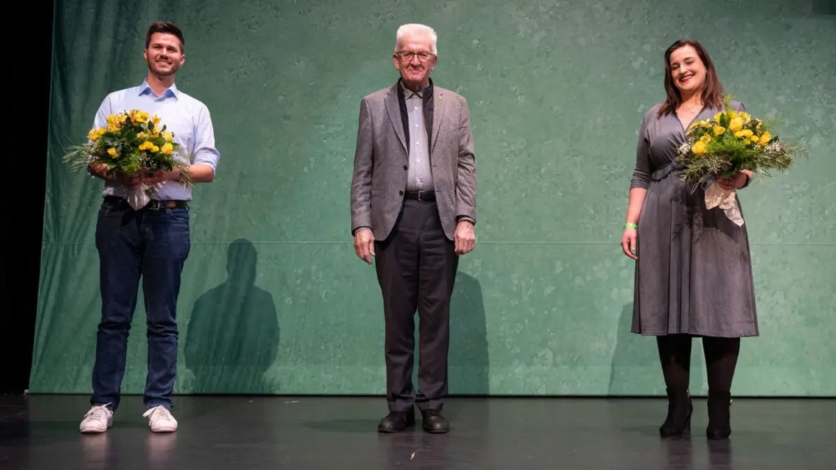 Ministerpräsident Winfried Kretschmann (Bildmitte), eingerahmt von den neuen Grünen-Landeschefs Lena Schwelling (rechts) und Pascal Haggenmüller (links).
04.12.2021, Baden-Württemberg, Heidenheim: Lena Schwelling (r), und Pascal Haggenmüller (l) stehen nach ihrer Wahl zum Landesvorsitz mit Winfried Kretschmann, Ministerpräsident von Baden-Württemberg (alle Bündnis 90/Die Grünen), beim Landesparteitag der Grünen Baden-Württemberg im Congress Centrum auf der Bühne. Foto: Marijan Murat/dpa +++ dpa-Bildfunk +++