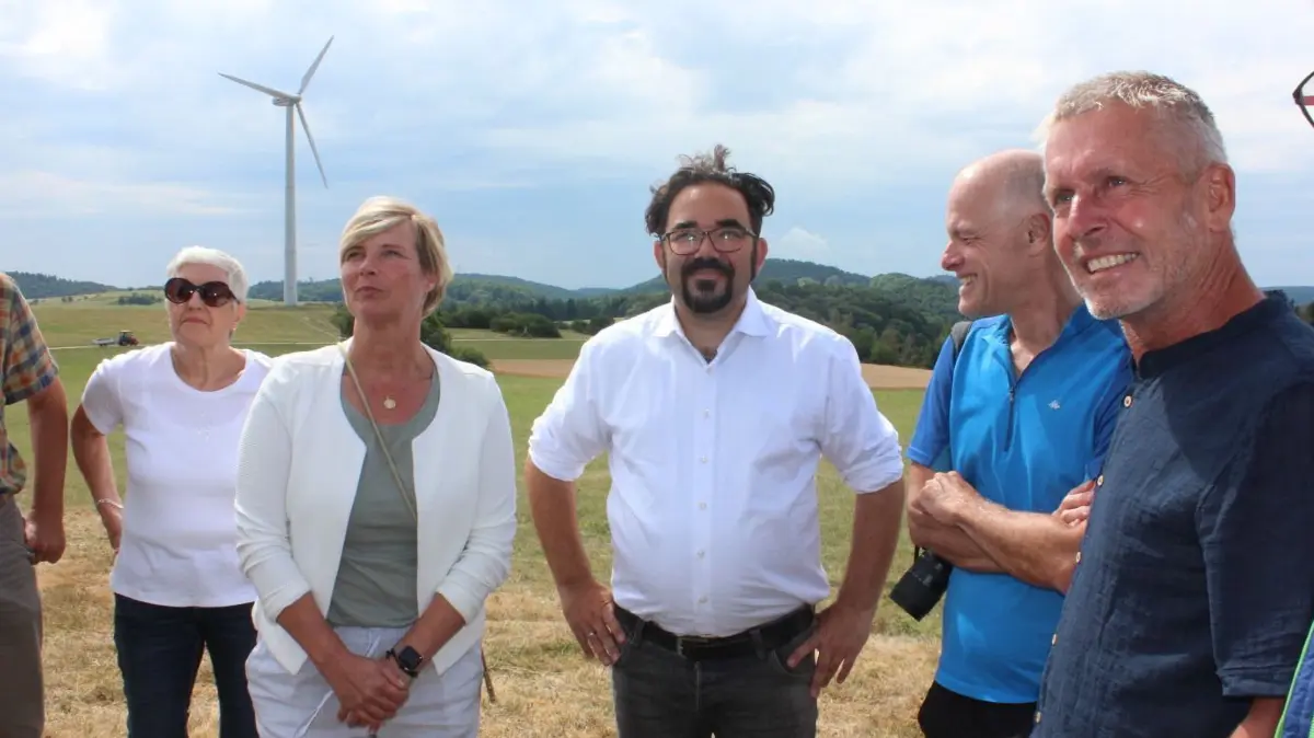 Drei Windräder drehen sich auf dem Melchinger Himmelberg, eins davon ist im Hintergrund zu sehen. Mit auf dem Foto: Bundestagsabgeordneter Chris Kühn (3. v. r.), die Landtagsabgeordnete Cindy Holmberg (2. v. l.) und Sowitec-Geschäftsführer Frank Hummel (r.). ⇥