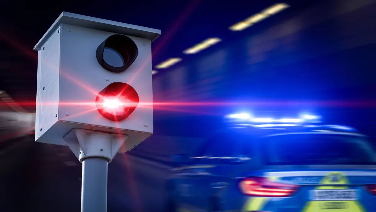 10 February 2024: Speed trap with red flashing light next to a police car with blue lights. Symbolic image of speed camera and speed measurement. PHOTOMONTAGE *** Radarfalle mit rotem Blitzlicht neben einem Polizeiauto mit Blaulicht. Symbolbild Blitzer und Geschwindigkeitsmessung. FOTOMONTAGE