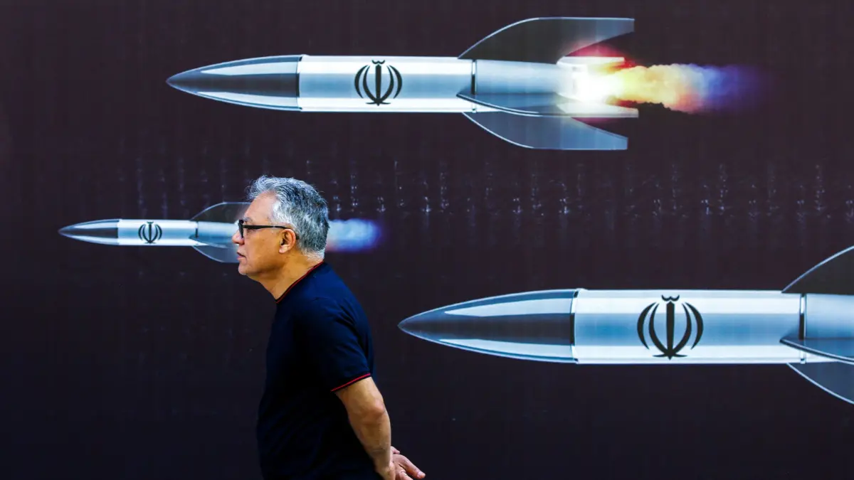 A man walks past a banner depicting missiles along a street in Tehran on April 19, 2024. Iran's state media reported explosions in the central province of Isfahan on April 19, as US media quoted officials saying Israel had carried out retaliatory strikes on its arch-rival. (Photo by AFP)