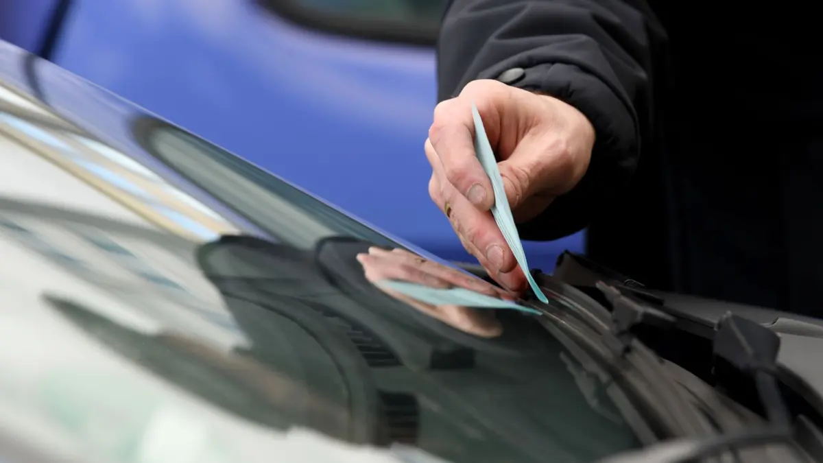 ARCHIV - 13.03.2020, Hessen, Frankfurt/Main: Ein Mitarbeiter der Städtischen Verkehrspolizei klemmt einen Strafzettel hinter den Scheibenwischer eines Pkw. Falschparker und Temposünder haben dem Landeshaushalt in Hessen 2022 laut der am Kasseler Regierungspräsidium angesiedelten Zentralen Bußgeldstelle (ZBS) gut 88,6 Millionen Euro überwiesen - das sind rund 22,3 Millionen Euro mehr als im Jahr zuvor. (zu dpa: «Neuer Bußgeldkatalog sorgt für mehr Einnahmen aus Verkehrsverstößen») Foto: Arne Dedert/dpa +++ dpa-Bildfunk +++
