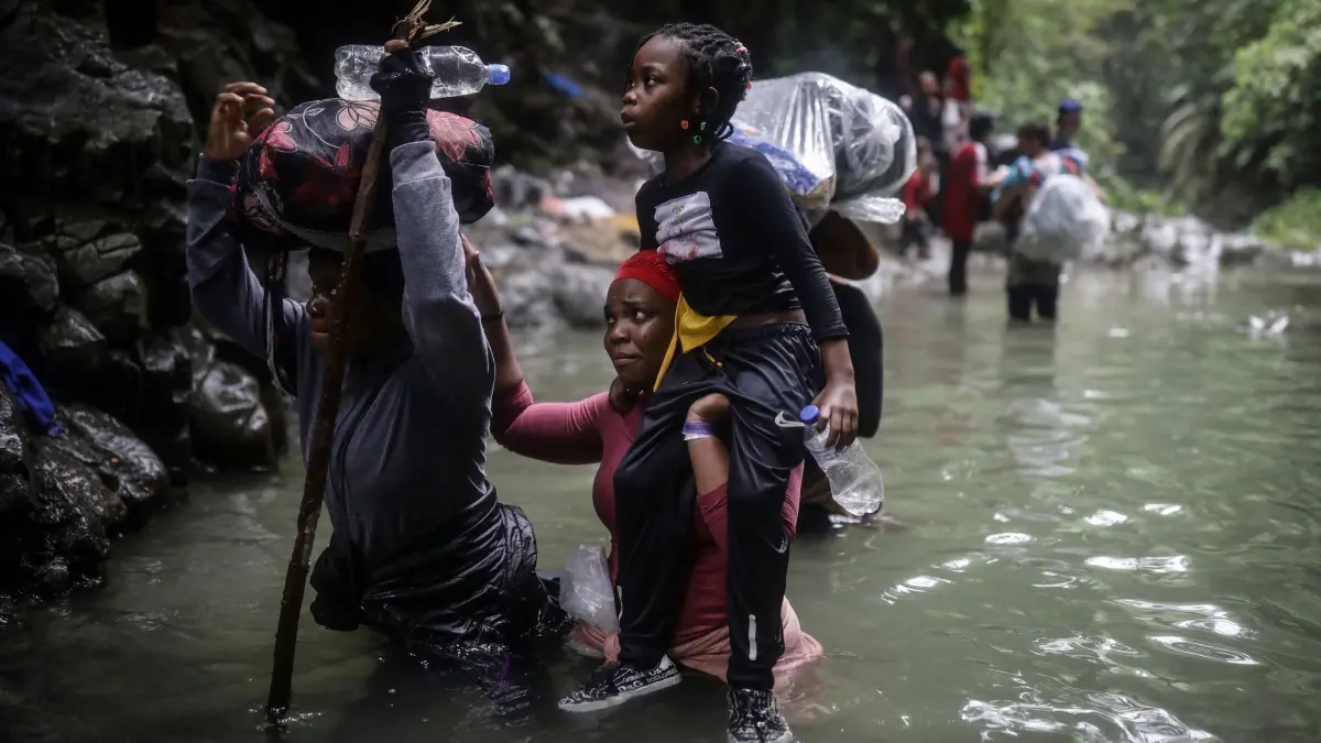 Migration in die USA: ARCHIV - 09.05.2023, Kolumbien, Darien Gap: Menschen aus Haiti waten durch Wasser, während sie den Darien Gap von Kolumbien nach Panama überqueren, in der Hoffnung, die USA zu erreichen. (zu dpa: «Unicef: Zehntausende Migrantenkinder durchqueren Darién-Dschungel») Foto: Ivan Valencia/AP/dpa +++ dpa-Bildfunk +++