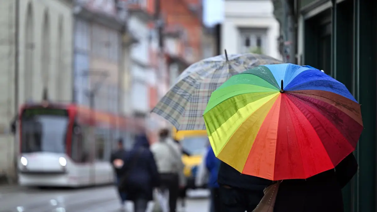 Regen und Gewitter in Thüringen: ARCHIV - 19.04.2024, Thüringen, Erfurt: Fußgänger laufen mit Regenschirmen durch die Marktstraße in Erfurt. Mit Regen und Schnee zeigt der Frühling in Thüringen an diesem Wochenende seine ungemütliche Seite. (zu dpa: «Wolken und Regen in Thüringen – am Samstag sind Unwetter möglich») Foto: Martin Schutt/dpa +++ dpa-Bildfunk +++