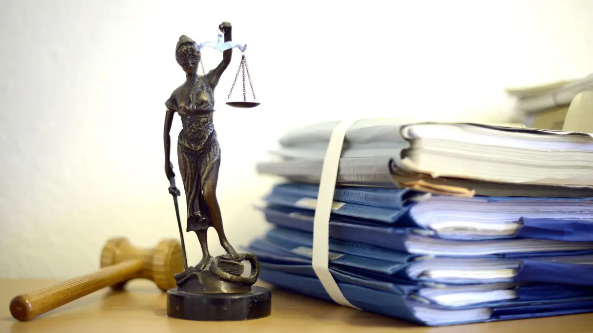 ARCHIV - Die modellhafte Nachbildung der Justitia steht am 15.07.2014 in einem Raum des Landgerichtes Duisburg neben einem Holzhammer und einem Aktenstapel. Auf den Richterbänken in Nordrhein-Westfalen bleibt das Kopftuch verboten. Das hat das NRW-Justizministerium klargestellt. Das Verwaltungsgericht Augsburg hatte das Kopftuch Ende Juni zumindest für dortige Rechtsreferendarinnen erlaubt. Ein Sprecher des Düsseldorfer Ministeriums sagte jedoch auf dpa-Anfrage: «Die Entscheidung des Verwaltungsgerichts Augsburg ist noch nicht rechtskräftig und dürfte eine Einzelfallentscheidung bleiben.» Foto: Volker Hartmann/dpa (zu dpa: «Kein Kopftuch auf Richterbänken in NRW » vom 19.07.2016) +++(c) dpa - Bildfunk+++