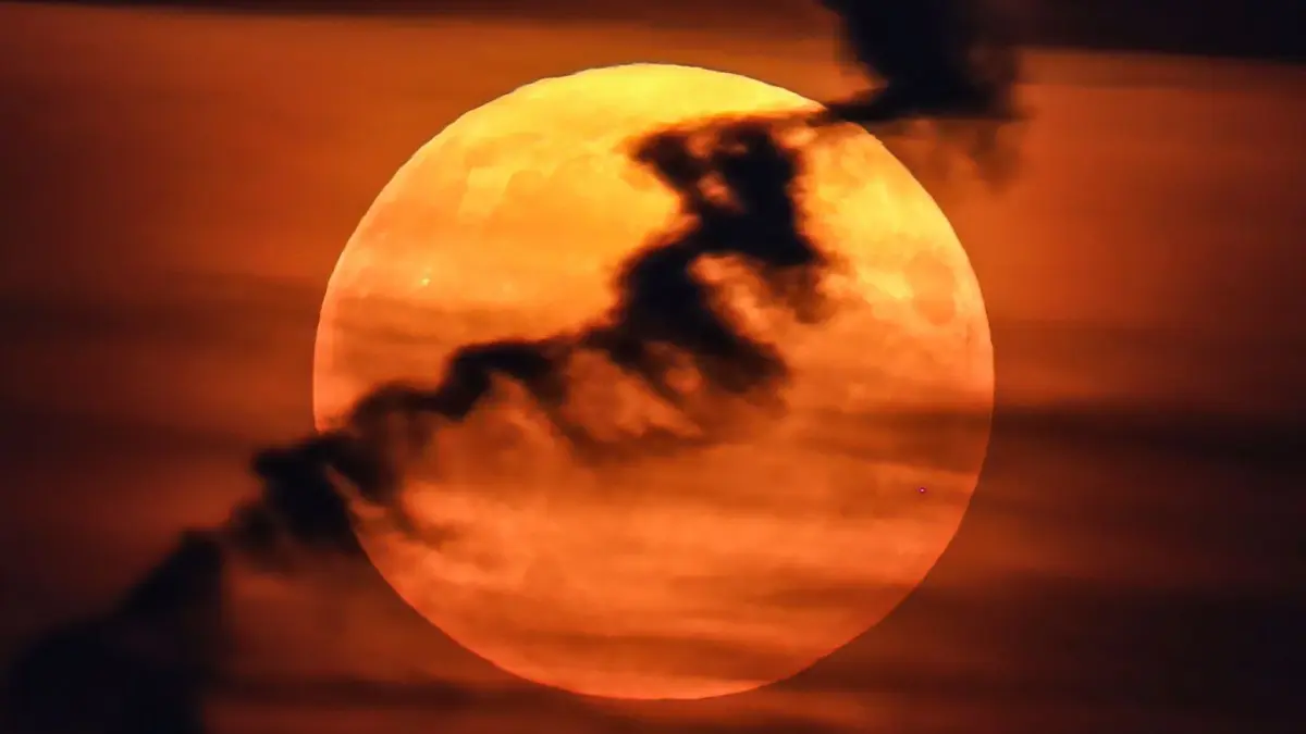 ARCHIV - 19.08.2024, Russland, St. Petersburg: Ein großer Vollmond erscheint hinter Wolken am roten Abendhimmel. Da er näher an der Erde ist als sonst und damit größer erscheint, wird er als Supermond bezeichnet. (zu dpa: «Doppelphänomen am Himmel: Vollmond mit partieller Finsternis») Foto: Artem Priakhin/SOPA Images/ZUMA Press Wire/dpa +++ dpa-Bildfunk +++