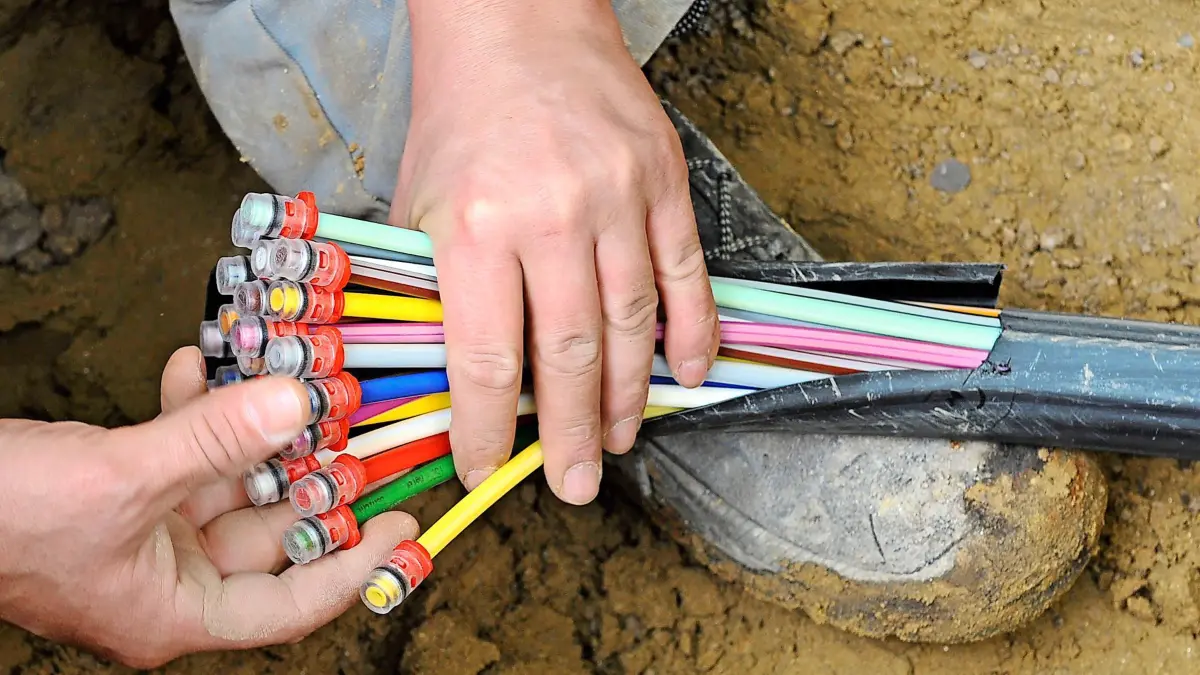 Breitbandausbau, Ein Mann fächert unter einer Straße in München ein Glasfaser-Kabel mit farbigen Einzelsträngen auseinander. Foto: Peter Kneffel/dpa (zu dpa-Meldung vom 24.08.2016) +++(c) dpa - Bildfunk+++