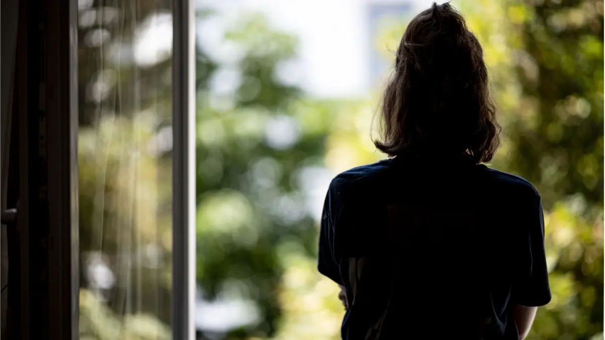 ARCHIV - 13.07.2021, Berlin: ILLUSTRATION - Eine Frau steht in ihrer Wohnung an einem Fenster. (gestellte Szene - zu dpa: «Decke über den Kopf und Ruhe - «Einsamkeit in Depression eingebaut» ») (zu dpa: «Alleinstehend häufigste Lebensform in Sachsen-Anhalt») Foto: Fabian Sommer/dpa +++ dpa-Bildfunk +++