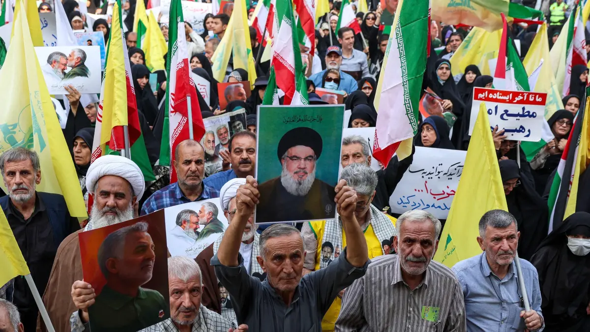 Iranians lift the flag of Hezbollah and a portrait of its slain leader Hassan Nasrallah during an anti-Israel rally in Tehran, on October 8, 2024. Iran warned Israel on October 8 against attacking any of its infrastructure amid fears of a possible Israeli assault on oil or nuclear sites following Iran's missile barrage last week. Tehran says its attack on Israel, when some 200 missiles were fired, was a response to the death in a Beirut air strike of Hassan Nasrallah, leader of the Iran-backed Lebanese movement Hezbollah, and of Hamas political leader Ismail Haniyeh in Tehran. (Photo by AFP)