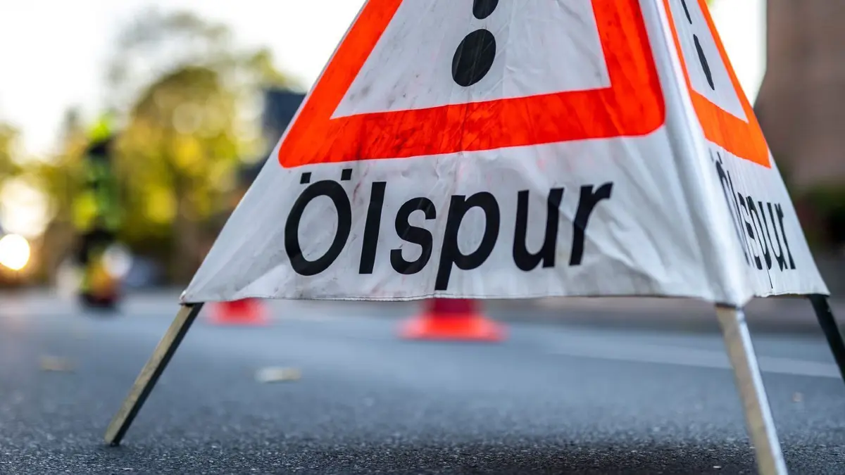 Symbolbild - Blaulicht: ARCHIV - 09.10.2021, Nordrhein-Westfalen, Wadersloh: Die Feuerwehr hat ein Warnschild mit der Aufschrift «Ölspur» auf die Fahrbahn gestellt. (zu dpa: «Kilometerlange Ölspur durch defektes Fass auf Lkw») Foto: David Inderlied/dpa +++ dpa-Bildfunk +++