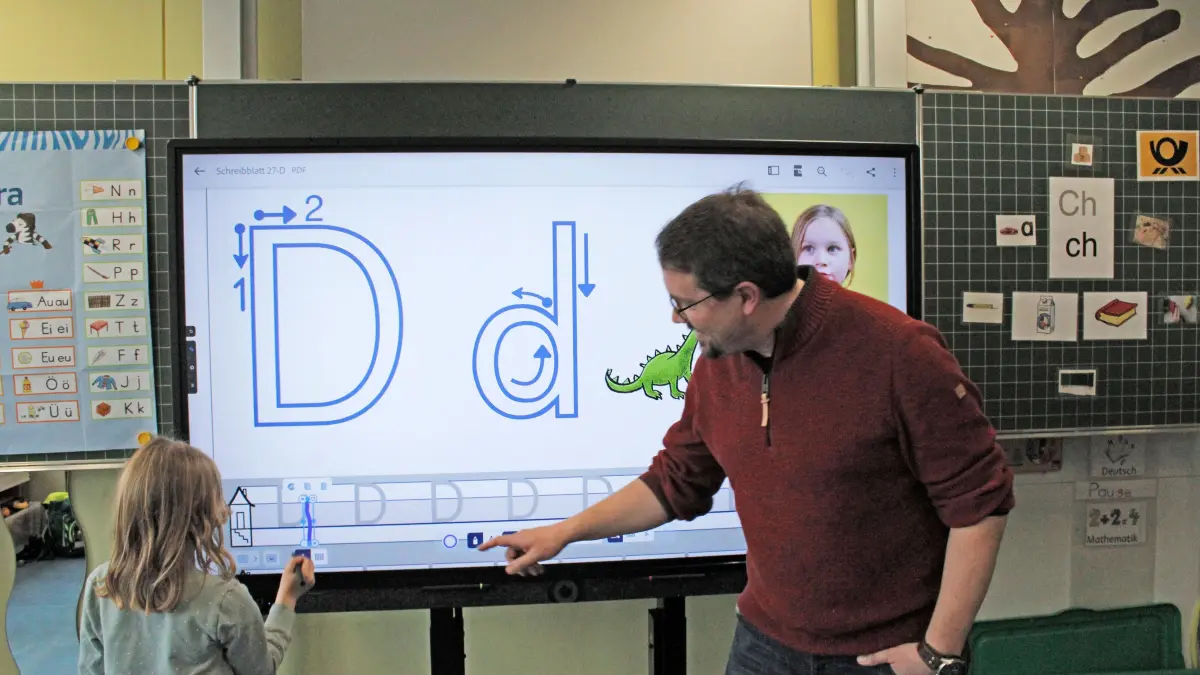 Der Schulleiter der Eutinger Grundschule Klaus Kaiser lehrt eine Schülerin an einer Digitalen Tafel das Schreiben. Die „Digitafel“ hat die herkömmliche Schultafel großteils abgelöst. Foto: Michael Stock (Archiv)