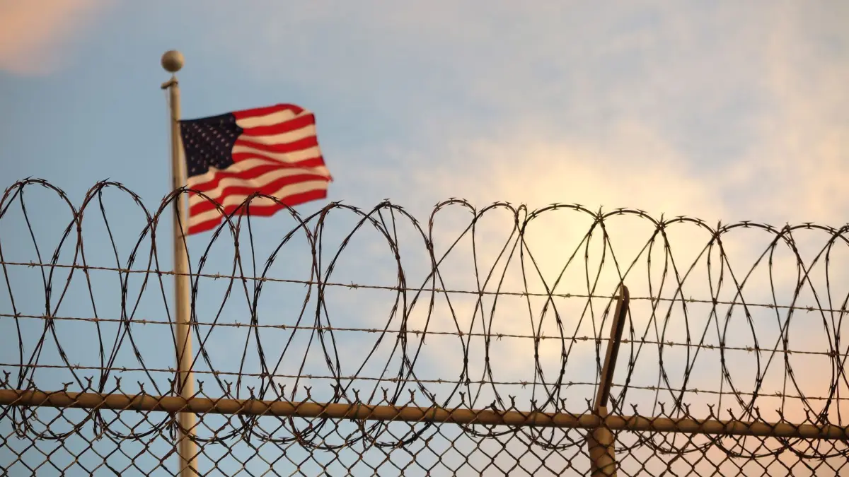 Terror vom 11. September: Pentagon will Justizdeal stoppen: ARCHIV - 16.10.2018, Kuba, Guantanamo Bay: Eine US-amerikanische Flagge weht hinter einem Stacheldrahtzaun im Wind. (zu dpa: «Terror vom 11. September: Pentagon will Justizdeal stoppen») Foto: Maren Hennemuth/dpa +++ dpa-Bildfunk +++