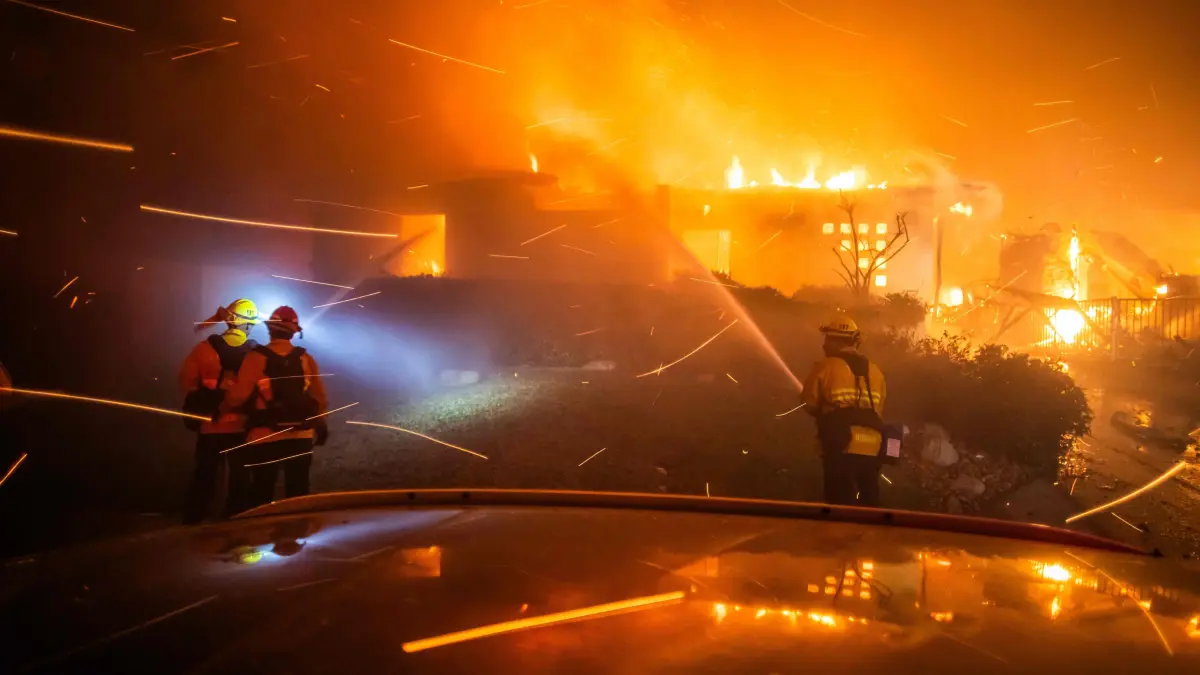 Powerful Winds Fuel Multiple Fires Across Los Angeles Area: LOS ANGELES, CALIFORNIA - JANUARY 8: Firefighters fight the flames from the Palisades Fire burning a house during a powerful windstorm on January 8, 2025 in the Pacific Palisades neighborhood of Los Angeles, California. The fast-moving wildfire is threatening homes in the coastal neighborhood amid intense Santa Ana Winds and dry conditions in Southern California. Apu Gomes/Getty Images/AFP (Photo by Apu Gomes / GETTY IMAGES NORTH AMERICA / Getty Images via AFP)