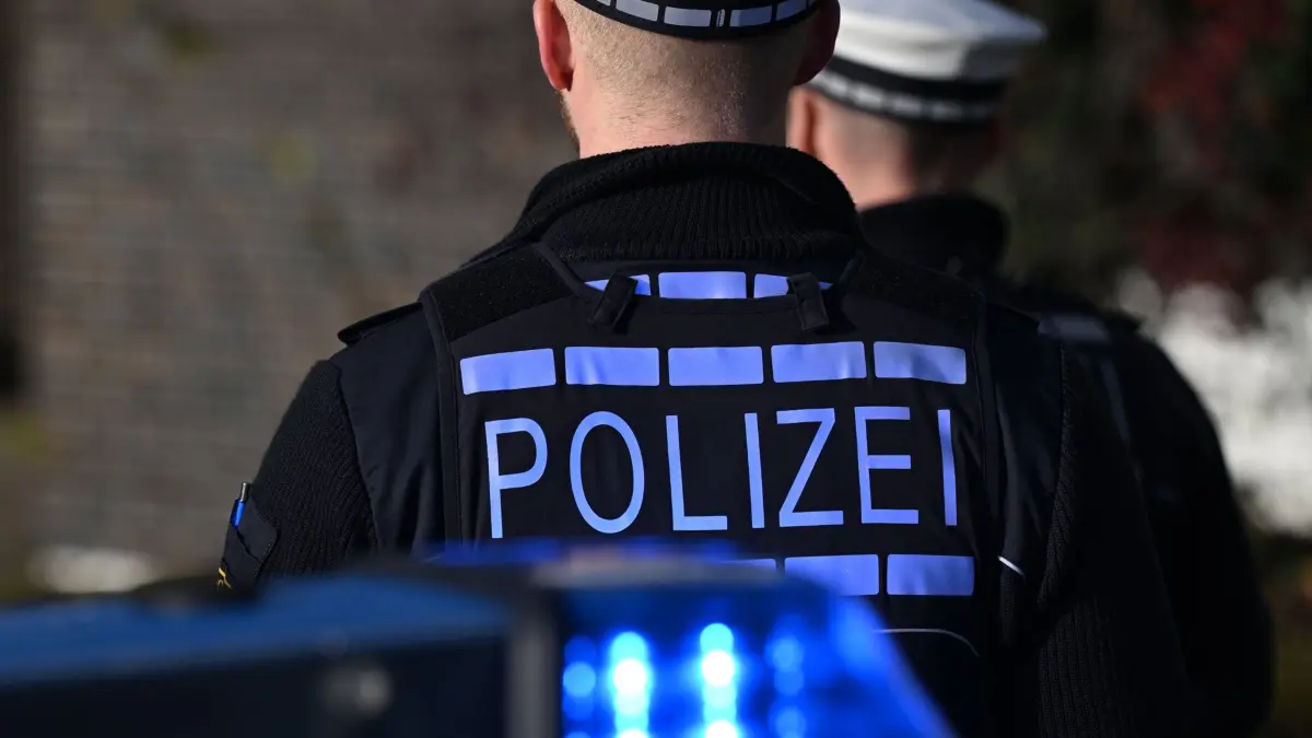 03.12.2024, Baden-Württemberg, Stuttgart: Das Logo der Polizei auf der Dienstkleidung eines Polizisten der vor einem Blaulicht steht (gestellte Szene). (zu dpa: «Mann fügt Frau mit Messer schwere Verletzungen zu») Foto: Bernd Weißbrod/dpa +++ dpa-Bildfunk +++