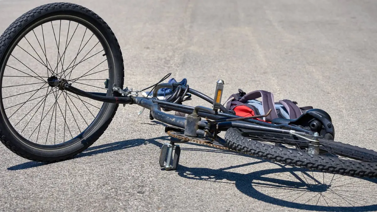 Torbole, Lake Garda, Italy - June 30, 2024: Symbolic image of a traffic accident involving a bicycle. Bicycle accident with bike on the road and objects scattered by the cyclist posed scene Aerial view *** Symbolbild Verkehrsunfall mit einem Fahrrad. Fahrradunfall mit Rad auf der Straße und verstreuten Gegenständen von dem Radfahrer gestellte Szene Luftaufnahme