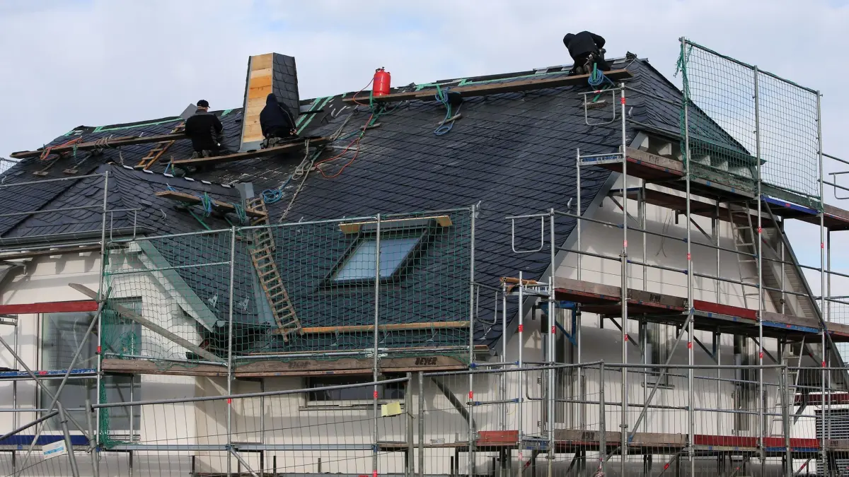 Hausbau in Rheinland-Pfalz: ARCHIV - 04.02.2015, Rheinland-Pfalz, Nieder-Olm: Männer arbeiten am 05.02.2015 in einem Neubaugebiet in Nieder-Olm (Rheinland-Pfalz) am Dach eines Neubaus. (zu dpa: «Studie: Neubau-Angebot in Rheinland-Pfalz und Saarland hoch») Foto: Fredrik von Erichsen/dpa +++ dpa-Bildfunk +++