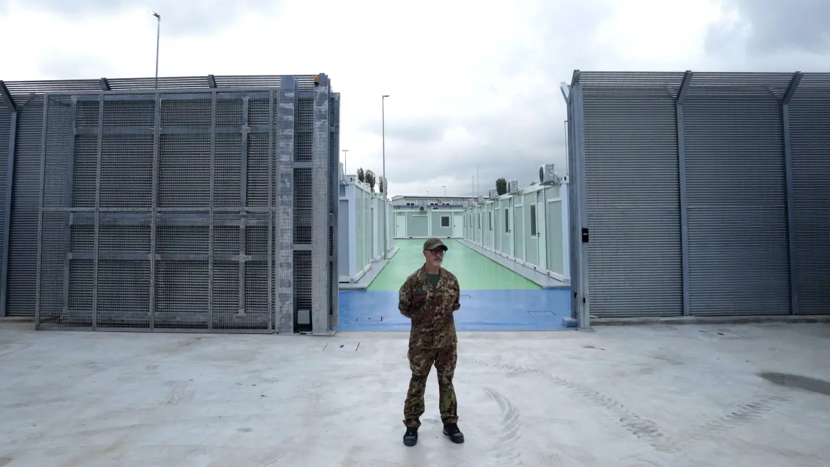 (FILES) An Italian police officer stands in a recently build Italian-run migrant centre at the port of Shengjin, some 60 kms northwest of Tirana, on October 11, 2024. Italy's government agreed on March 28, 2025 to change who will be held in its migrant centres in Albania, but experts warned the legal challenges that have effectively frozen the scheme until now remain. The government announced after a council of ministers meeting that its two facilities designed to be processing centres for potential asylum seekers intercepted at sea would now also serve as repatriation centres to hold migrants due to be sent back to their home countries. (Photo by Adnan Beci / AFP)
