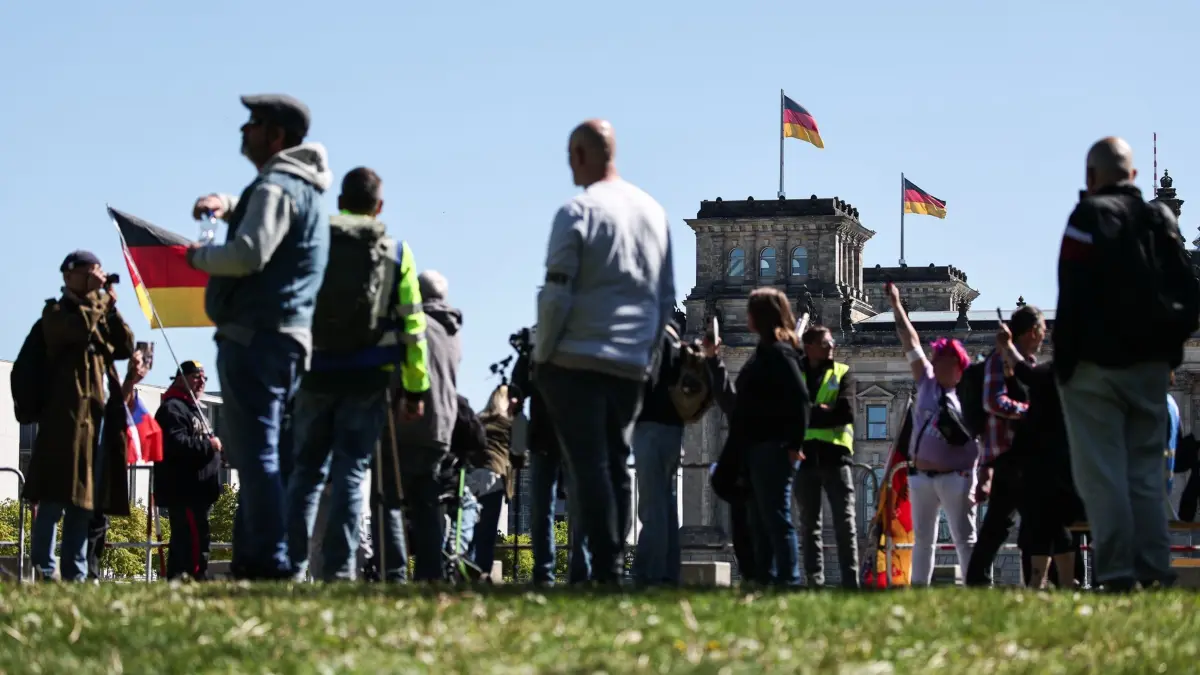 Bundestag - Kanzlerwahl: 06.05.2025, Berlin: Demonstranten mit einer Deutschland-Flagge stehen vor dem Reichstagsgebäude. Der designierte Bundeskanzler F. Merz (CDU)ist bei der Kanzlerwahl im Bundestag im ersten Wahlgang durchgefallen. Foto: Hannes P Albert/dpa +++ dpa-Bildfunk +++