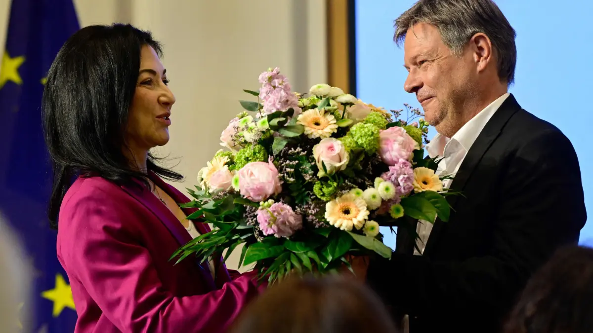 German former Minister of Economics and Climate Protection Robert Habeck (R) gives a bouquet of flowers to his successor German Economy and Energy Minister Katherina Reiche during a handover ceremony at the Ministry in Berlin on May 7, 2025, one day after a new government was sworn in. (Photo by John MACDOUGALL / AFP)