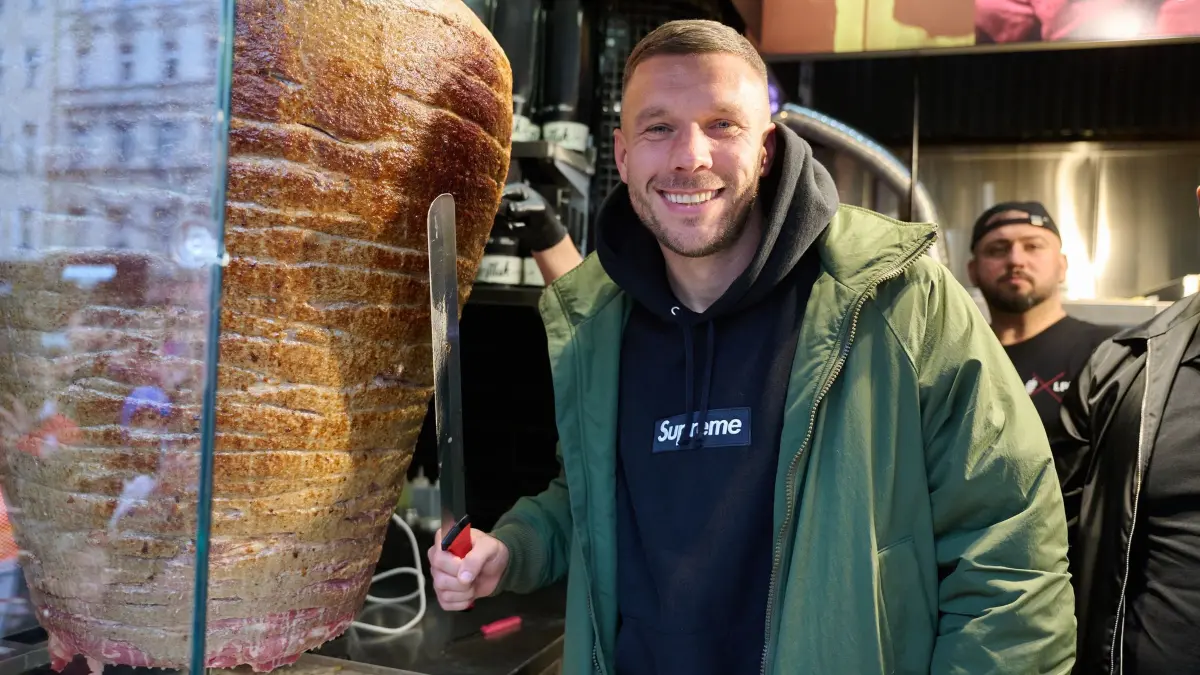 Lukas Podolski: ARCHIV - 03.03.2024, Berlin: Lukas Podolski, ehemaliger Fußballprofi und Unternehmer, steht an einem Drehspieß während der Eröffnung von Podolskis Döner-Imbiss. (zu dpa: «Podolski überall: «Einer von der Straße» macht Business») Foto: Annette Riedl/dpa +++ dpa-Bildfunk +++
