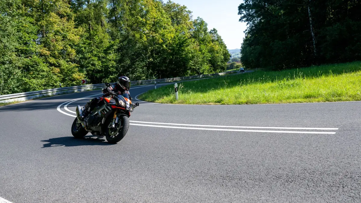 ARCHIV - 17.09.2023, Bayern, Untermerzbach-Memmelsdorf: Ein Motorradfahrer fährt in einer Kurve im Hambach zwischen Ebern und Untermerzbach (Unterfranken). Das sonnige Wetter lockt zu Ausflügen. (zu dpa: «Im Süden gibt es die meisten Motorräder») Foto: Pia Bayer/dpa +++ dpa-Bildfunk +++