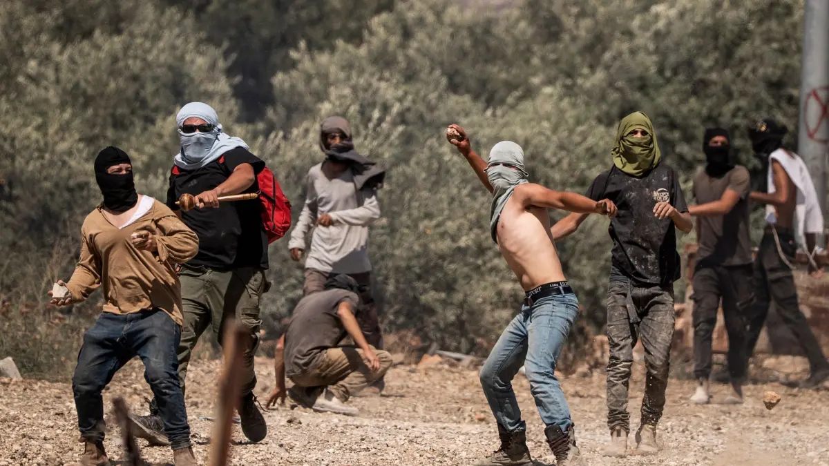 Nahostkonflikt - Westjordanland: ARCHIV - 26.06.2025, Palästinensische Gebiete, Turmusaya: rechtsgerichtete israelische Siedler werfen Steine auf palästinensische Dorfbewohner während eines Angriffs auf das Westjordanlanddorf Turmusaya. (zu dpa: «Berichte: Zwei Tote bei Siedlergewalt im Westjordanland») Foto: Ilia Yefimovich/dpa +++ dpa-Bildfunk +++