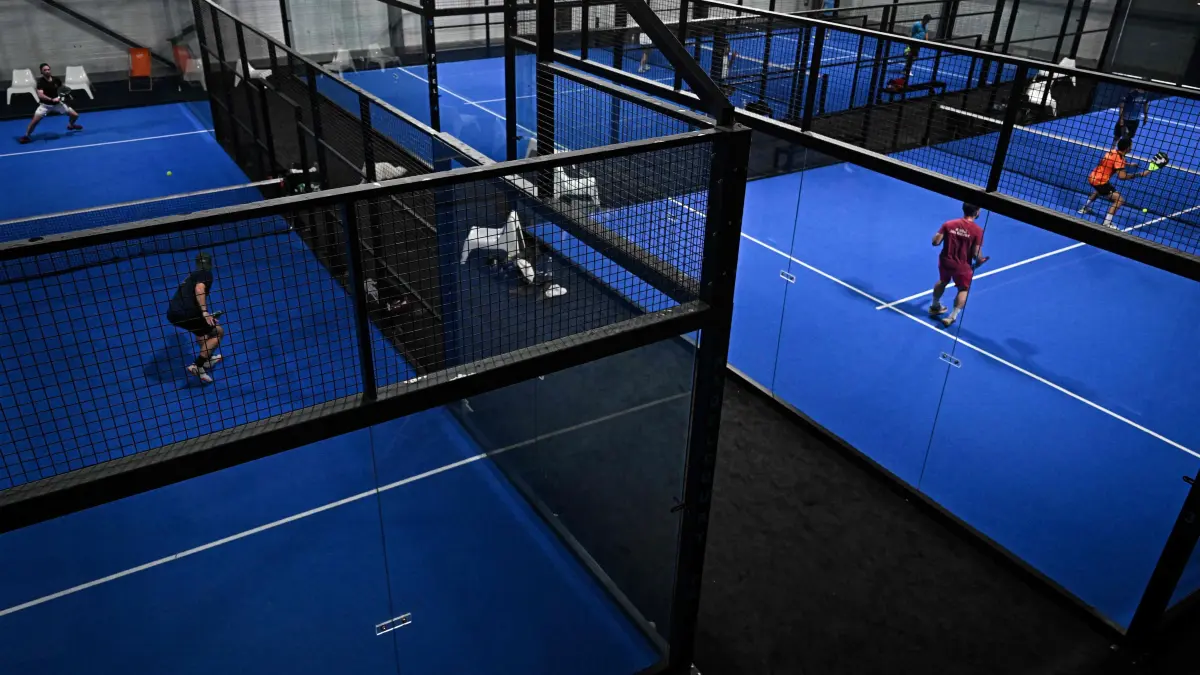 Men play on padel tennis courts at the Beziers Indoor Padel club in Beziers, southern France on July 22, 2025. The padel, a mixture of tennis and squash, is played in teams of two on a court that is typically surrounded by glass walls which players can bounce balls off. (Photo by GABRIEL BOUYS / AFP)