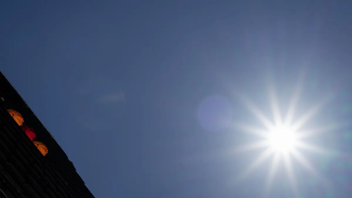 Sonne auf dem Balkon: 12.08.2025, Berlin: Drei Sonnenschirme stehen nebeneinander auf dem Balkon eines Hauses in der Leipziger Straße. Foto: Soeren Stache/dpa +++ dpa-Bildfunk +++