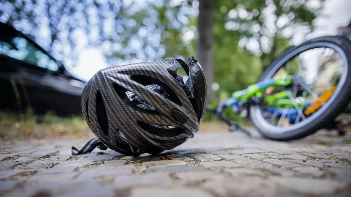 Symbolfoto zum Thema Fahrradunfall gestellte Szene. Ein zerbrochener Fahrradhelm liegt neben einem Fahrrad auf einer Strasse. Berlin, 21.08.2024. Berlin Deutschland *** Symbol photo on the topic Bicycle accident posed scene A broken bicycle helmet lies next to a bicycle on a street Berlin, 21 08 2024 Berlin Germany Copyright: xThomasxTrutschel/photothek.dex