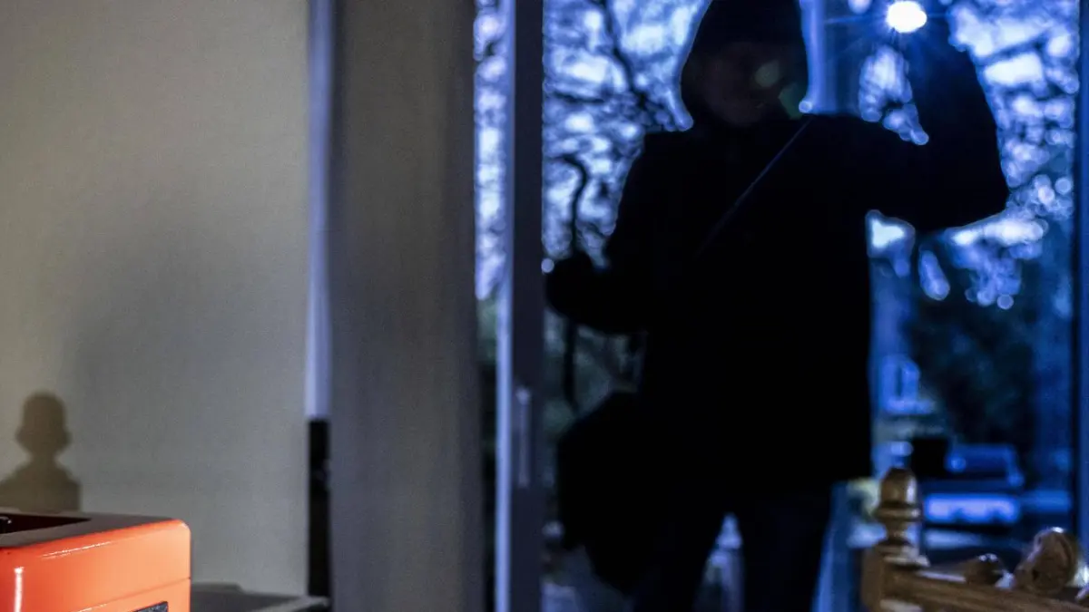 Symbolbild Wohnungseinbruch, Täter ist von der Gartenseite her, in eine Wohnung eingedrungen und sucht nach Beute, Geldkassette, Wertgegenstände, Geld, Technik, Einbrecher *** Symbolic picture burglary, perpetrator has entered an apartment from the garden side and is looking for loot, cash box, valuables, money, technology, burglar
