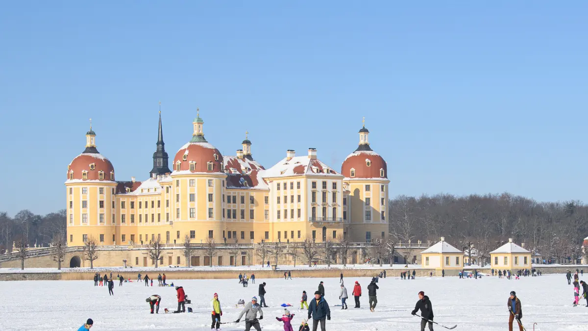 Zahlreiche Menschen sind auf dem zugefrorenen Schlossteich vor dem Schloss Moritzburg, dem einstigen Jagdschloss der Wettiner, unterwegs. +++ dpa-Bildfunk +++