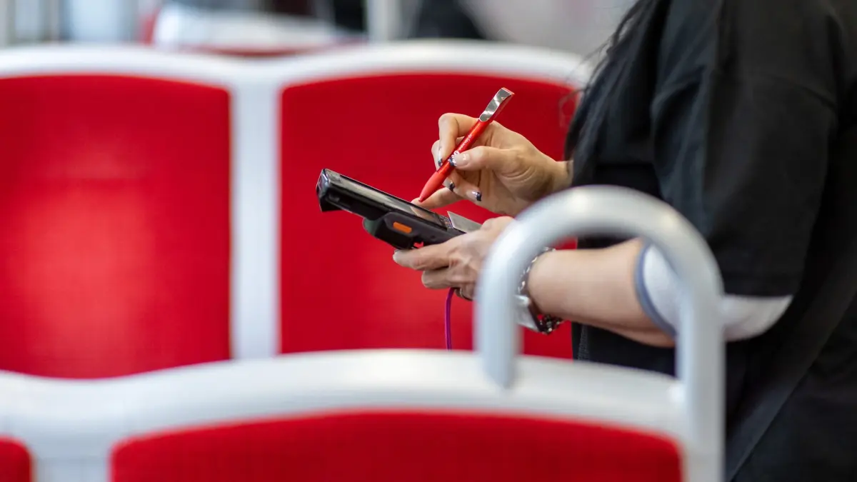 Eine Fahrkartenkontrolleurin kontrolliert einen Fahrgast: ARCHIV - Kein Fahrschein bei der Kontrolle? Wird nachträglich belegt, dass ein gültiges Ticket vorhanden war, reduziert sich die Strafe erheblich. (zu dpa: «Bahnfahrkarte nicht dabei? Nachreichen spart Geld») Foto: Daniel Karmann/dpa/dpa-mag - Honorarfrei nur für Bezieher des Dienstes dpa-Magazin +++ dpa-Magazin +++
