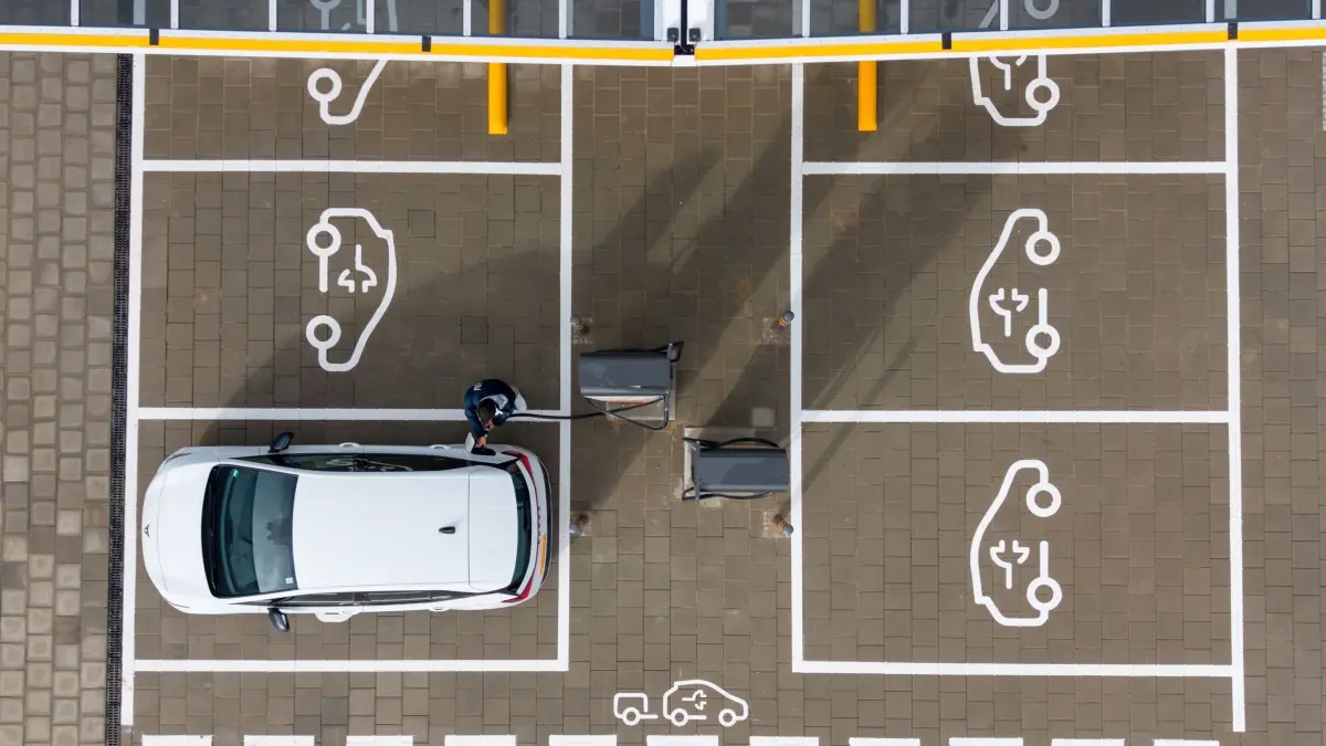 Schnellladepark für Elektromobile: ARCHIV - 22.10.2025, Sachsen, Klipphausen: Ein Mann steht auf einem Ladepark der EnBW Energie Baden-Württemberg AG und steckt ein Ladekabel in den Tankstutzen eines Elektroautos (Aufnahme mit einer Drohne). (zu dpa: «Zahl der E-Autos steigt - Quote weiterhin niedrig») Foto: Sebastian Kahnert/dpa +++ dpa-Bildfunk +++