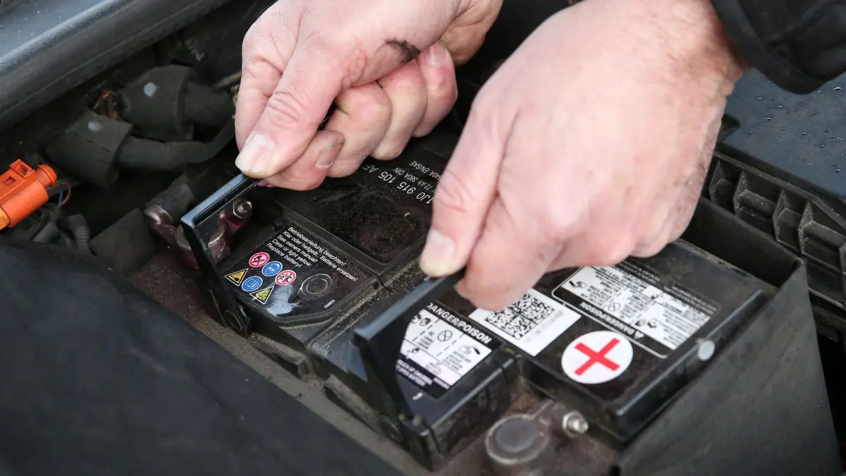 Mann wechselt eine Autobatterie