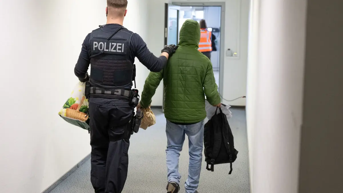 Abschiebungen: ARCHIV - 25.02.2025, Hessen, Frankfurt/Main: Ein Polizeibeamter bringt einen Mann zu einem Abschiebeflug nach Pakistan. (zu dpa: «Weiterer Straftäter nach Syrien abgeschoben») Foto: Boris Roessler/dpa +++ dpa-Bildfunk +++