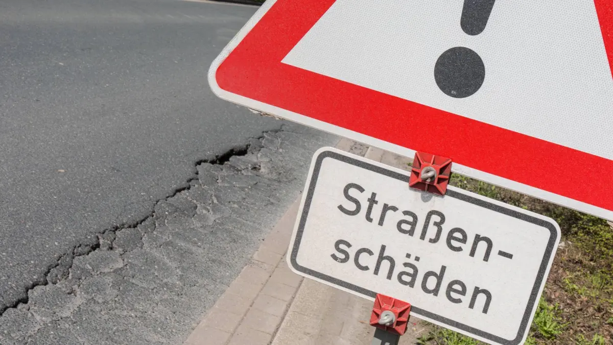 16.04.2018, Hamm, Deutschland, GER - Verkehrsschild mit dem Hinweis auf Strassenschäden dahinter ein Schlagloch auf einer Strasse. *** 16 04 2018 Hamm Germany GER Road sign with the indication of road damage behind it a pothole on a road