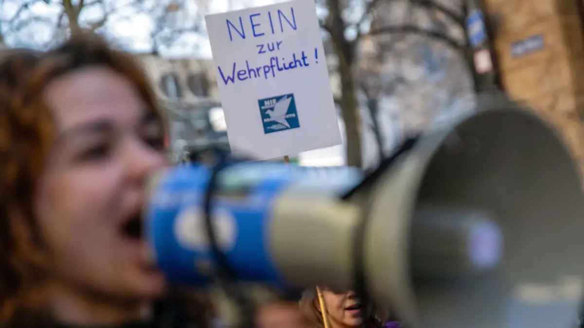 Bundesweiter Schulstreik gegen Wehrpflicht - Bamberg: 05.03.2026, Bayern, Bamberg: Eine junge Frau spricht in ein Megafon, während hinter ihr ein Plakat mit der Aufschrift "Nein zur Wehrpflicht!" in die Höhe gehalten wird. Schüler und Schülerinnen demonstrieren in Bamberg gegen die Wehrpflicht. Am gleichen Tag gibt es einen bundesweiten Schulstreik als Protest gegen die Wehrdienst-Pläne der Bundesregierung. Das Gesetz für den neuen Wehrdienst war am 1. Januar in Kraft getreten. Foto: Pia Bayer/dpa +++ dpa-Bildfunk +++