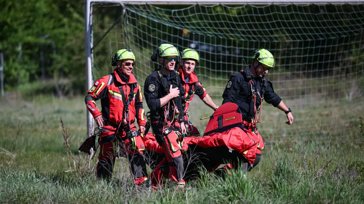 Feuerwehrmänner platzieren den Bergesack mit Puppe am Boden.