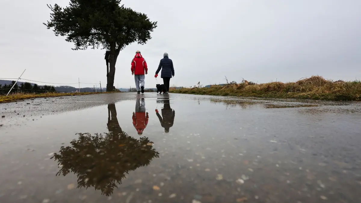 Frühling in Baden-Württemberg: ARCHIV - 01.03.2026, Baden-Württemberg, Riedlingen: Spaziergänger sind mit ihrem Hund im Regen unterwegs. (zu dpa: «Eisheiligen beginnen mit Dauerregen im Schwarzwald») Foto: Thomas Warnack/dpa +++ dpa-Bildfunk +++