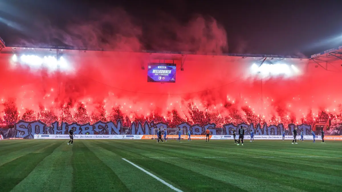 Magdeburger Fans brennen Pyro ab: ARCHIV - 24.01.2026, Sachsen-Anhalt, Magdeburg: Fußball: 2. Bundesliga, 1. FC Magdeburg - Dynamo Dresden, 19. Spieltag, Avnet Arena. Fans von 1. FC Magdeburg zünden Pyrotechnik. (zu dpa: «Krawalle in 2. Liga: Anklage wegen versuchten Mordes») Foto: Andreas Gora/dpa +++ dpa-Bildfunk +++