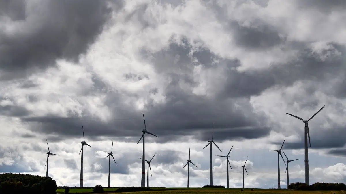 Grauer Himmel über Windrädern: ARCHIV - 25.09.2020, Hessen, Wolfhagen: Dunkle Wolken ziehen über mehrere Windräder hinweg. (zu dpa: «Mehr Geld für Kitas - Windrad-Pflichterträge für Kommunen») Foto: Swen Pförtner/dpa +++ dpa-Bildfunk +++