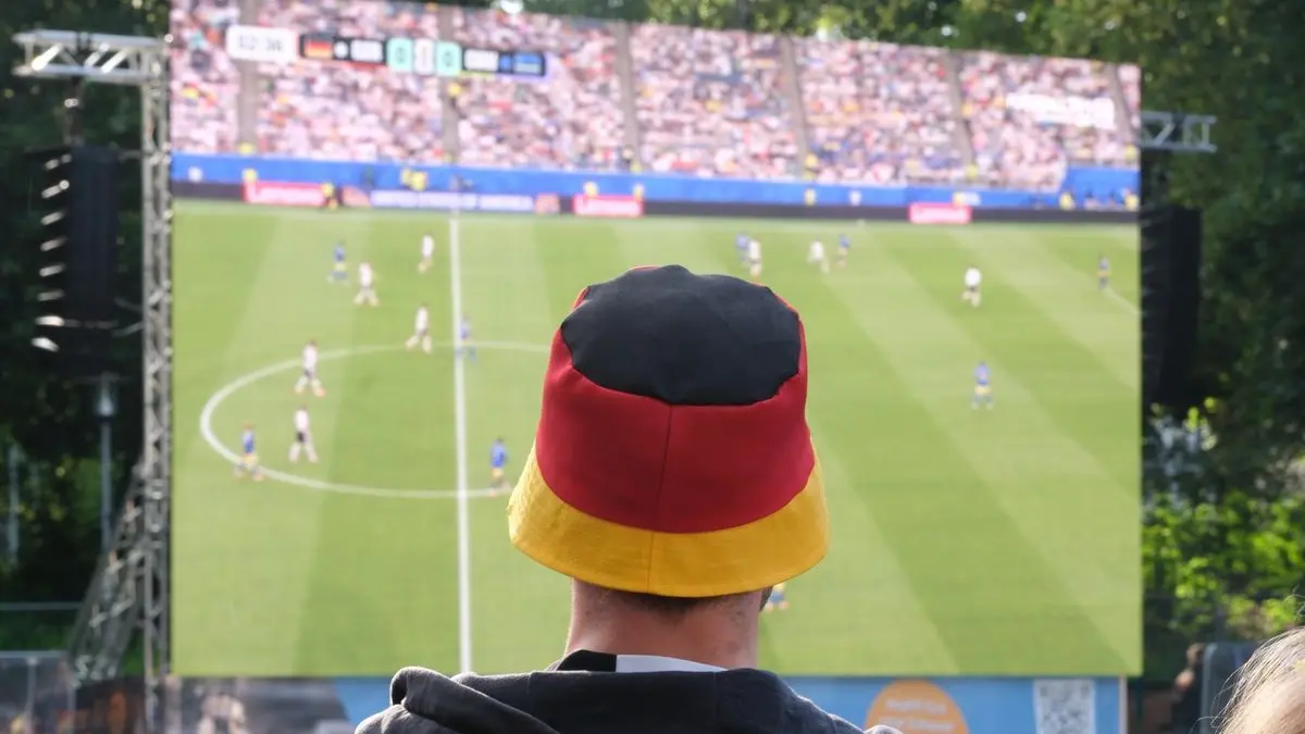 Ein Fan trägt beim Public Viewing einen Fischerhut in Deutschlandfarben.