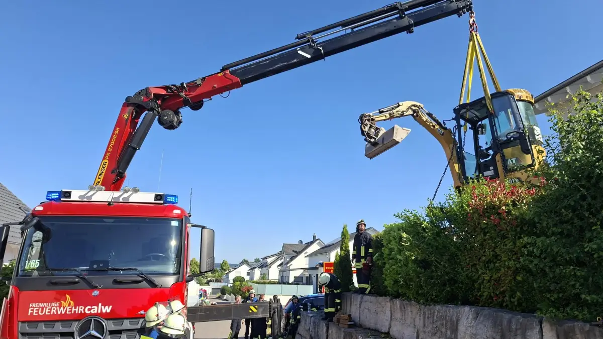 Feuerwehr hebt Bagger mit Kran auf die Straße