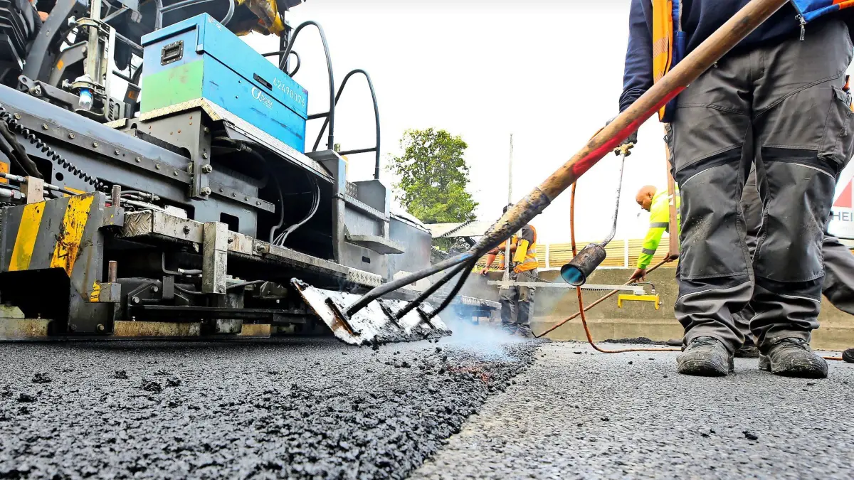 ARCHIV - 02.10.2020, Nordrhein-Westfalen, Mülheim: Arbeiter tragen auf einer Autobahn eine neue Asphaltdecke auf. (zu dpa: «Bitumen-Preis verdoppelt: Iran-Krieg verteuert Straßenbau») Foto: Roland Weihrauch/dpa +++ dpa-Bildfunk +++
