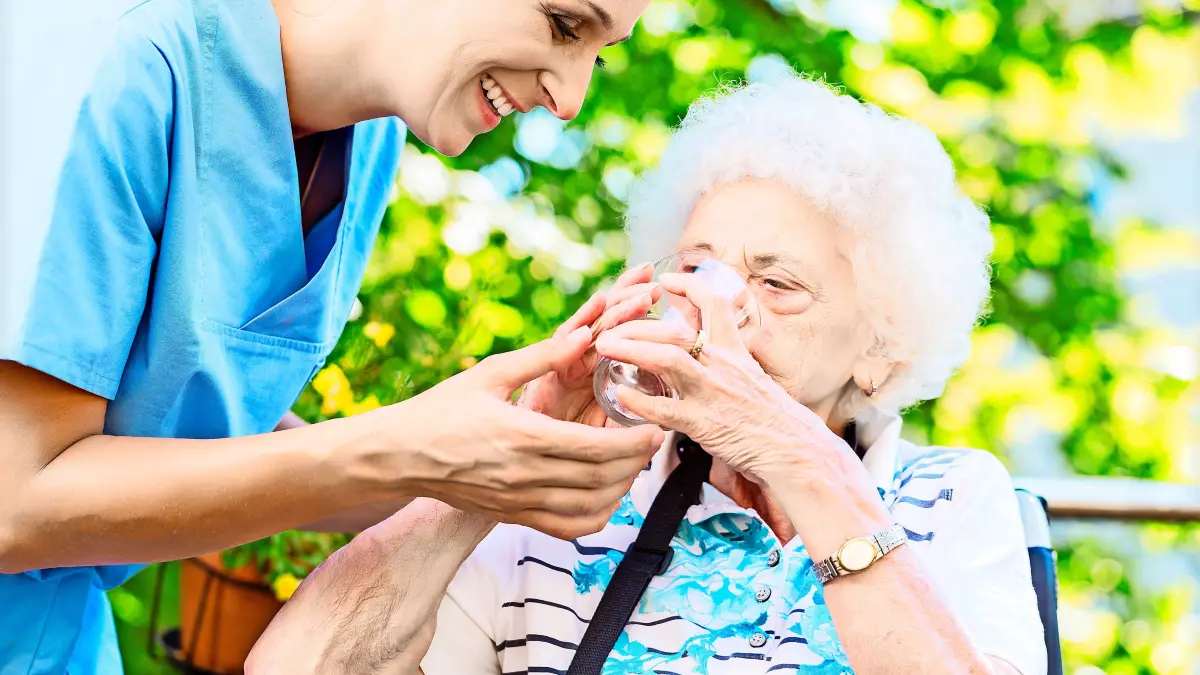 Geriatric nurse giving glass of water to senior woman